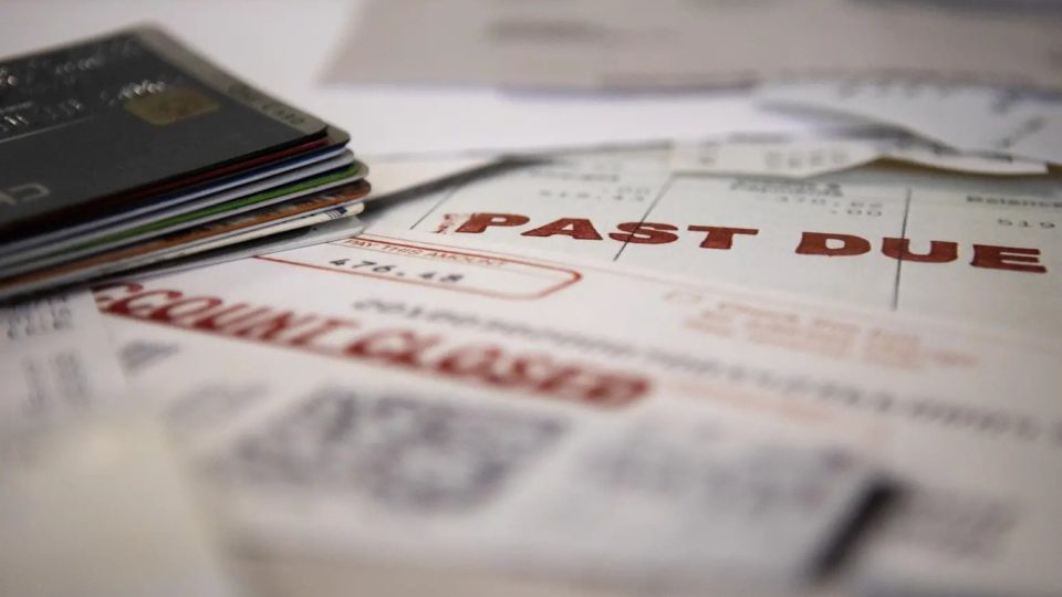 A stack of bills marked PAST DUE next to a pile of credit cards