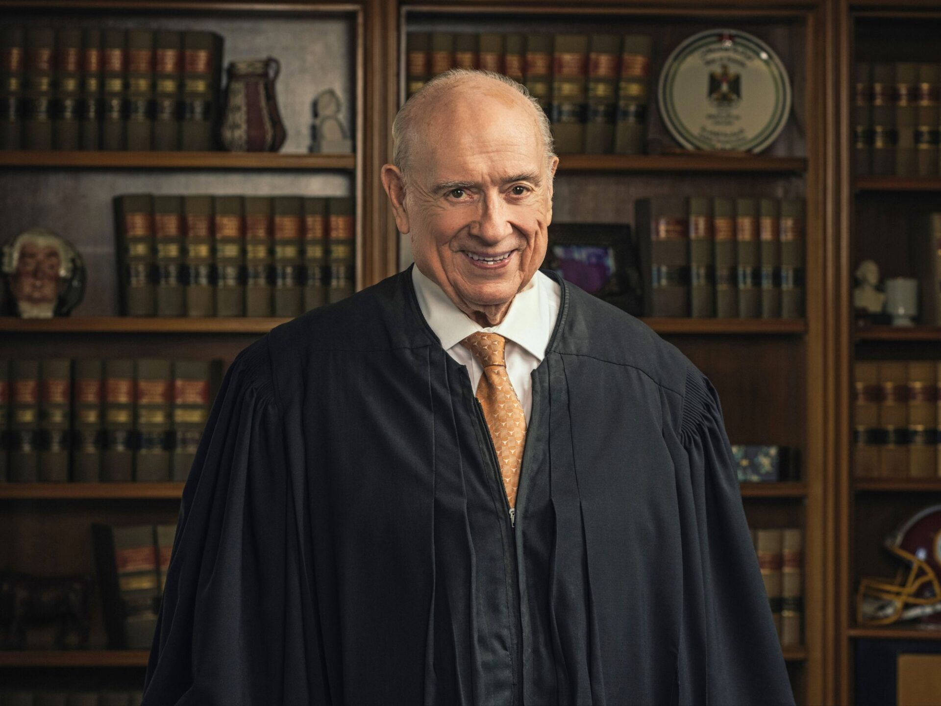 Formal photo of Judge Lamberth in black robe standing in front of case filled with books