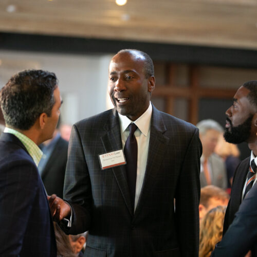 Man in a business suit speaks with others at a networking event