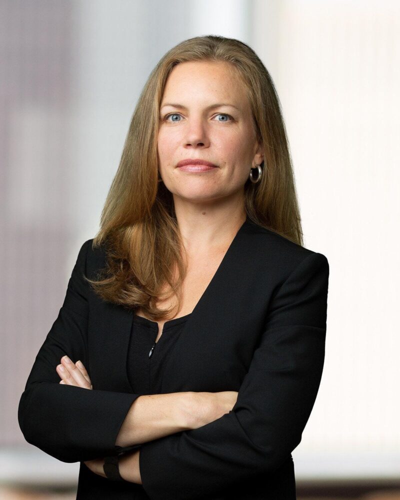 Portrait of Hilary Preston in a black suit with her arms crossed.