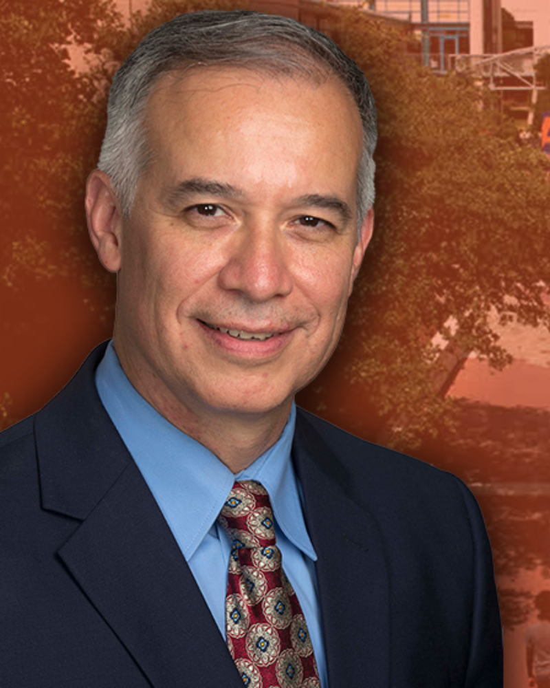 Headshot of Carlos Martinez in front of an orange background of UTSA campus