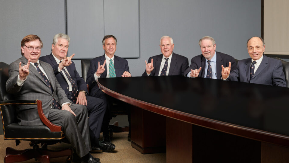 Six men in suits sitting at table