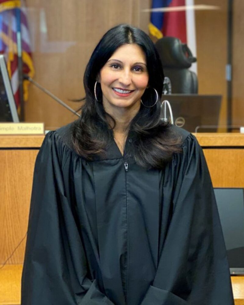 Judge Dimple Malhotra standing in front of a Judge desk