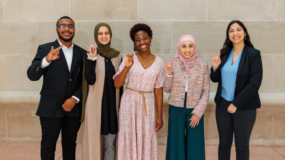 Five Cohort Members smiling with Hook Em signs