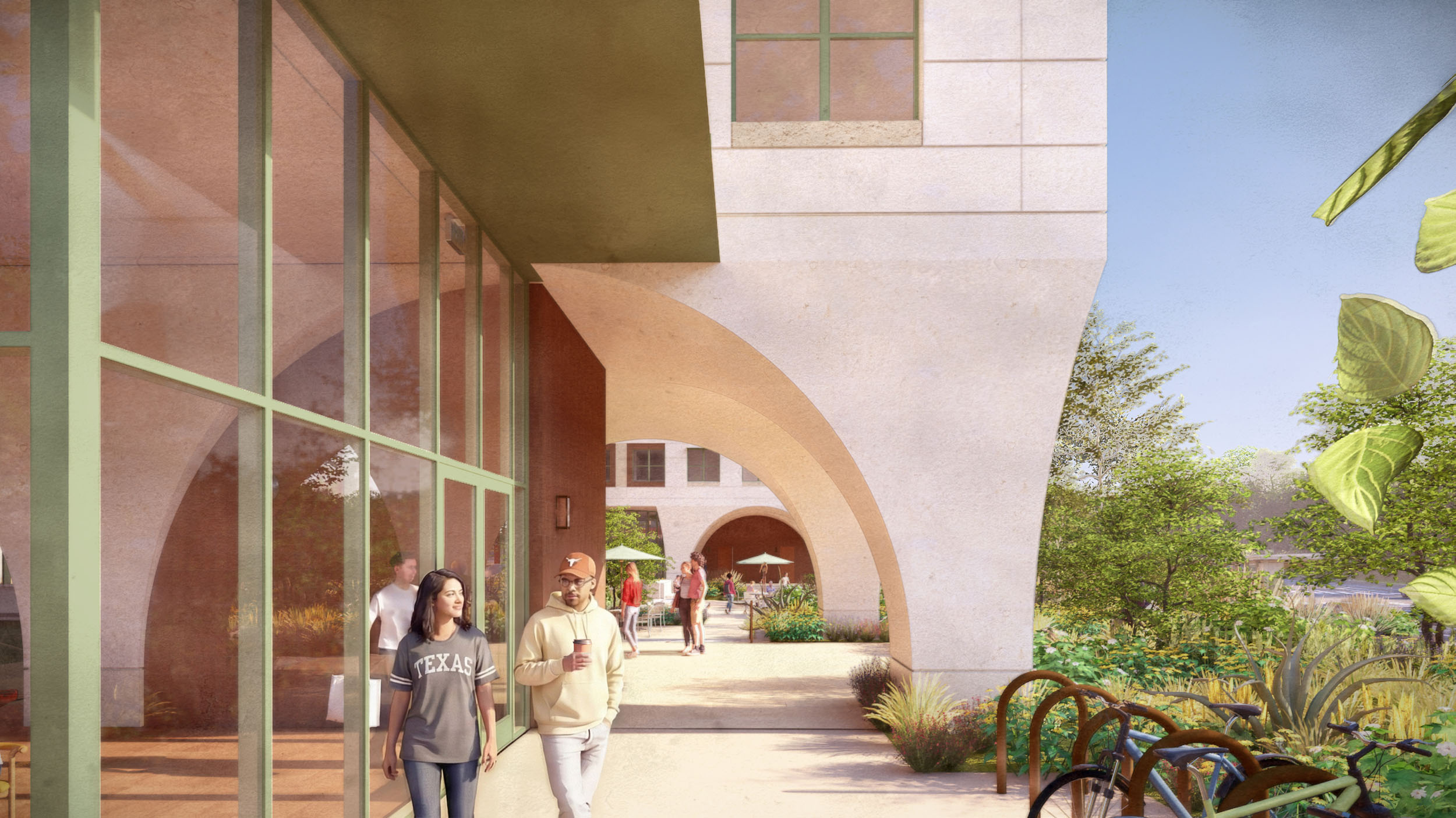 Two students walk together under a covered archway along the outside of a building by the café entry. Bikes are parked nearby, plants line the path, and more students gather at outdoor tables in the background.